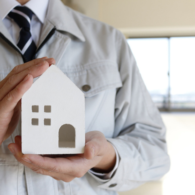 家の模型を持った作業員